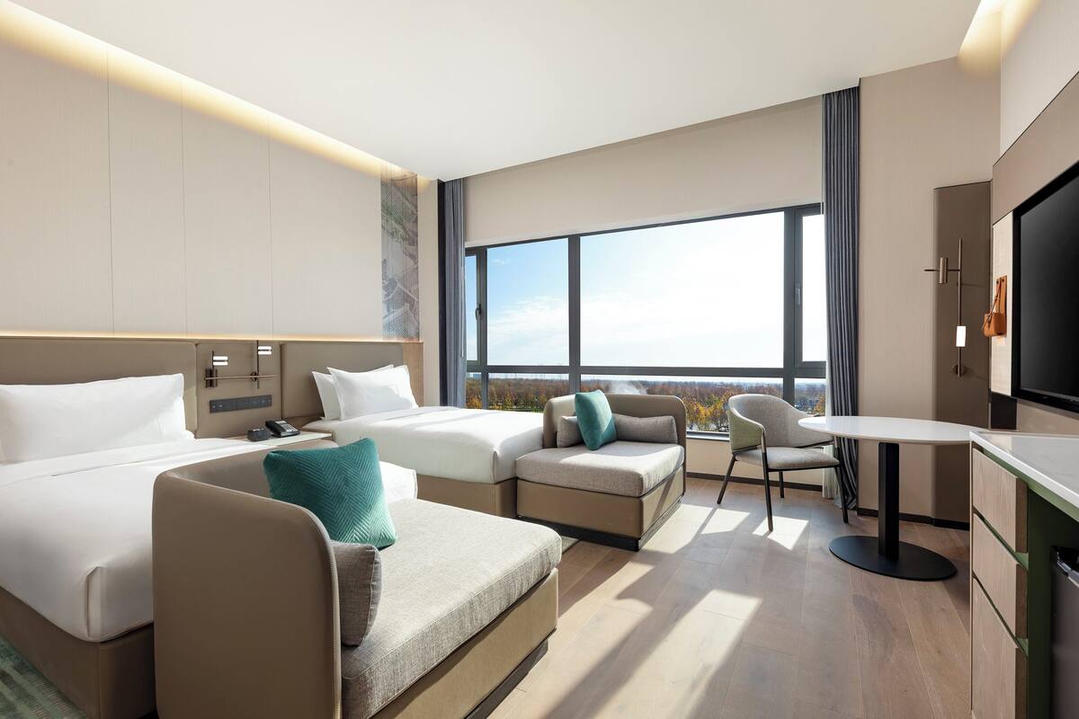 A modern hotel room with a large bed, a sofa, a small table, and a TV.