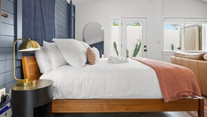 Een moderne slaapkamer met een groot bed, een bedlampje, een spiegel en uitzicht naar buiten.