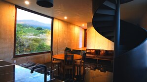 A modern interior with a wooden dining table and chairs, a leather sofa, and a spiral staircase. - Casa del Sol - CasaBlanca. Pool, privacy and mountain views (Oaxaca de Juárez)