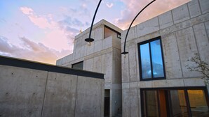 A modern building with concrete exterior walls, large windows, and hanging light fixtures. - Casa del Sol - CasaBlanca. Pool, privacy and mountain views (Oaxaca de Juárez)