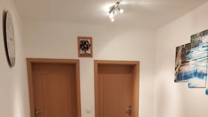 Ein Zimmer mit zwei Holztüren, einem runden Holztisch und drei beigen Sesseln.