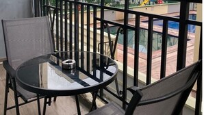 A balcony with a glass table and two chairs, overlooking a residential area with multi-story buildings and a playground. - 3 Bedroom En-Suite, Wi-Fi, Secured, 24/7 Power (Lagos)