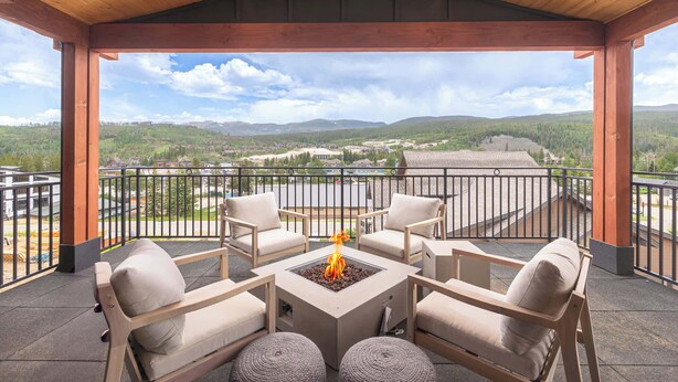 A covered outdoor seating area with a fire pit, wooden furniture, and a view of a mountainous landscape. - Prime Village Access | Walkable (Winter Park)