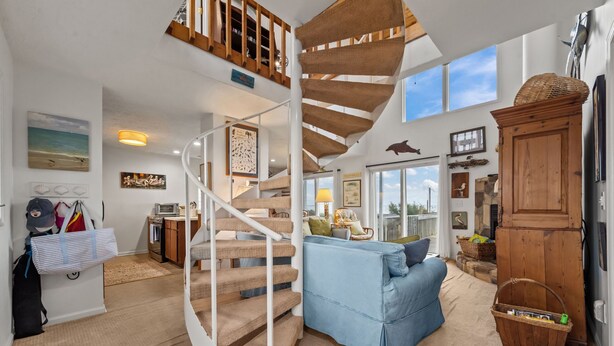 Un vaste espace de vie agrémenté d’un escalier en colimaçon, d’un canapé bleu et d’une armoire en bois.