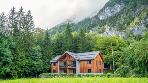 A wooden cabin with a sloped roof, surrounded by dense forest and mountains. - Apartment Presseggersee Top 4 (Hermagor)