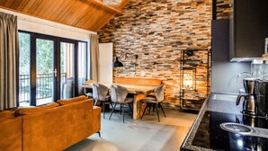 A modern kitchen with a stone backsplash, a wooden dining table, and a black countertop. - Apartment Presseggersee Top 4 (Hermagor)