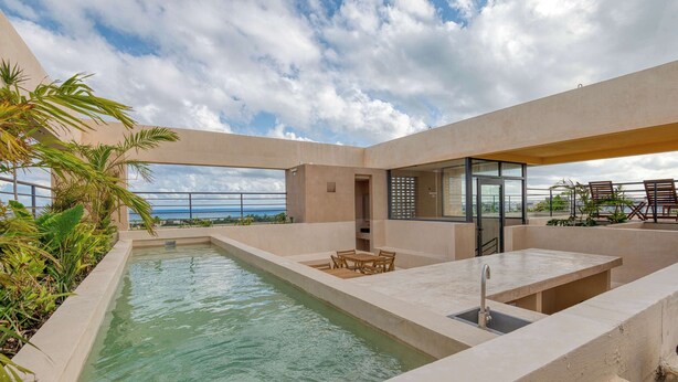A rooftop pool with a seating area and a glass-enclosed space. - Nalú: Loft with private plunge pool and ocean view (Playa del Carmen)