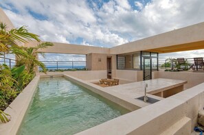 Una piscina en la azotea con zona de estar y espacio cubierto de vidrio.