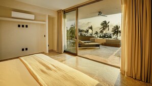 Quarto de hotel moderno com uma grande porta de vidro deslizante que dá para uma varanda com vista para palmeiras e uma piscina.