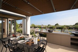 An outdoor dining area with a table set for four, surrounded by chairs, and a view of a swimming pool and greenery. - Villa Alba di Sereno with Pool (Vodnjan)