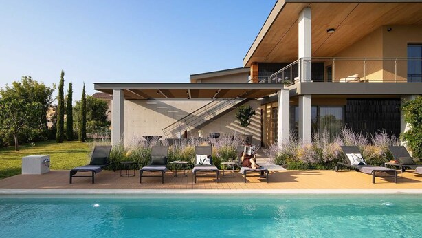 Ett modernt hus med en swimmingpool, utomhusmöbler och en täckt uteplats.