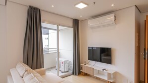 Een moderne woonkamer met een flatscreen televisie, een bank en een schuifdeur naar een balkon.