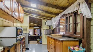 Een landelijke keuken met houten kastjes, een magnetron en een spoelbak.