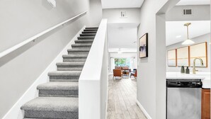 Une cuisine moderne équipée d’un lave-vaisselle, un coin repas avec une table et des chaises, et un escalier menant à un autre niveau.