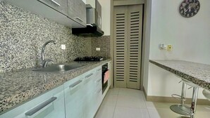 Eine moderne Küche mit Granit Arbeitsplatten, Edelstahlgeräten und einem Zweitürschrank.