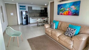 Ein modernes Wohnzimmer mit einem beigefarbenen Ledersofa, einem grünen Sessel und einem farbenfrohen Gemälde an der Wand.