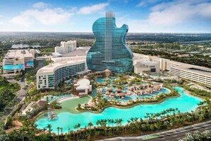 Ett semesterhotell med en byggnad formad som en gitarr, flera pooler och en frodig trädgårdsanläggning.