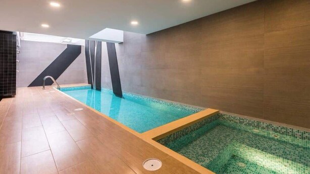 A modern indoor swimming pool with a wooden deck and tiled walls. - Comfort and Space 3bed /2.5 bath centric location (Miraflores)