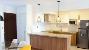 A modern kitchen with a central island, stainless steel appliances, and pendant lighting. - Comfort and Space 3bed /2.5 bath centric location (Miraflores)