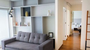 A modern living room with a grey sofa, a wooden coffee table, and a bookshelf with patterned decor. - Comfort and Space 3bed /2.5 bath centric location (Miraflores)