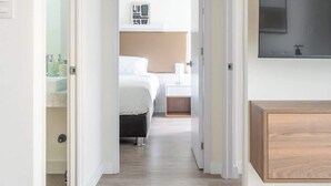 A hotel room with a bed, bedside table, and a TV mounted on the wall. - Sight 1707 · Ocean View 2BR Stylish Apt • Pool, Gym & Parking (Lima)
