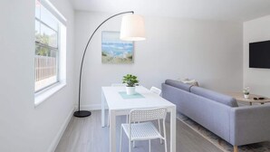 Een moderne woonkamer met een witte tafel, een grijze bank en een vloerlamp.