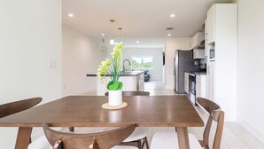 Ein stilvoller Essbereich mit Holztisch und Stühlen, einer Vase mit Blumen und Blick in die Küche und das Wohnzimmer.