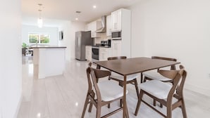 Una cocina moderna con armarios blancos, electrodomésticos de acero inoxidable y una isla central.