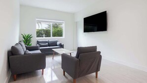 Una sala de estar moderna con un sofá gris, una mesa de centro y un televisor de pantalla plana montado en la pared.