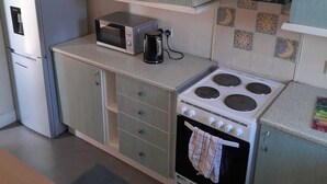 A compact kitchen with a refrigerator, microwave, toaster, stove, and cabinets. - A 2 bed flat in clentral Dumfries, excellent walkability to all amenities. (Dumfries)