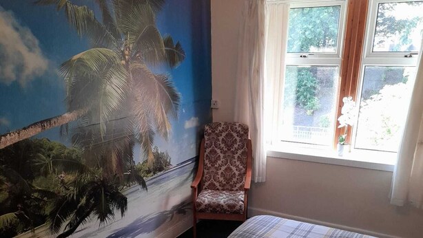 A bedroom with a bed, a chair, a wall mural, and a window. - A 2 bed flat in clentral Dumfries, excellent walkability to all amenities. (Dumfries)