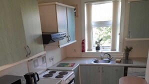 A compact kitchen with a stove, microwave, sink, and cabinets. - A 2 bed flat in clentral Dumfries, excellent walkability to all amenities. (Dumfries)