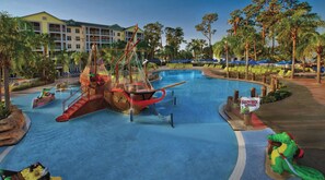 Une grande piscine dotée d’un espace de jeux sur le thème d’un bateau de pirates, de chaises longues et de palmiers.