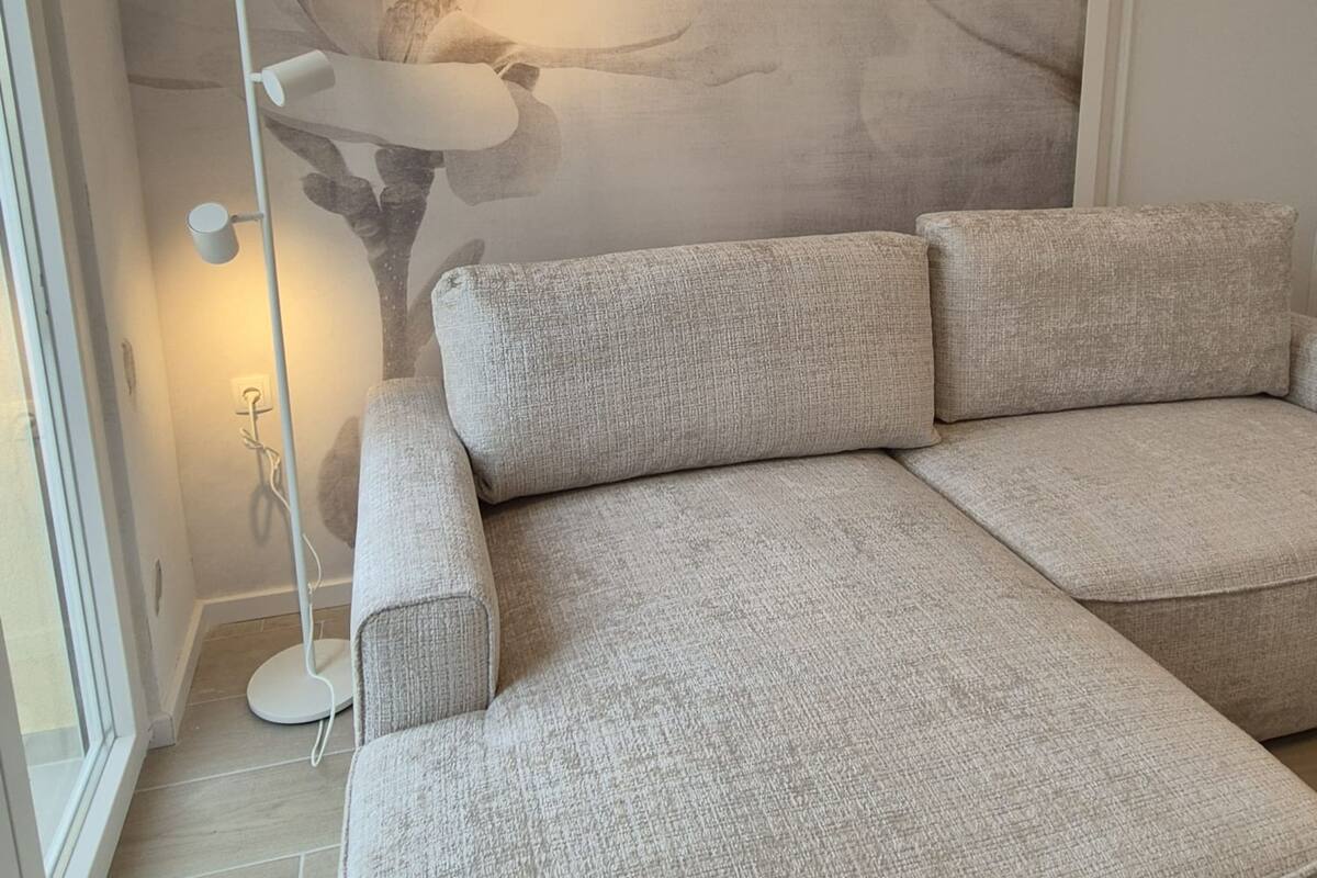 Un salon moderne avec un canapé d’angle, une lampe sur pied et une fresque murale.