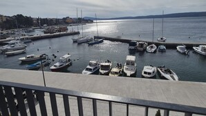 A marina with various boats docked, a clear sky, and a distant view of hills. - Apartments Rivijera 2 (Crikvenica)