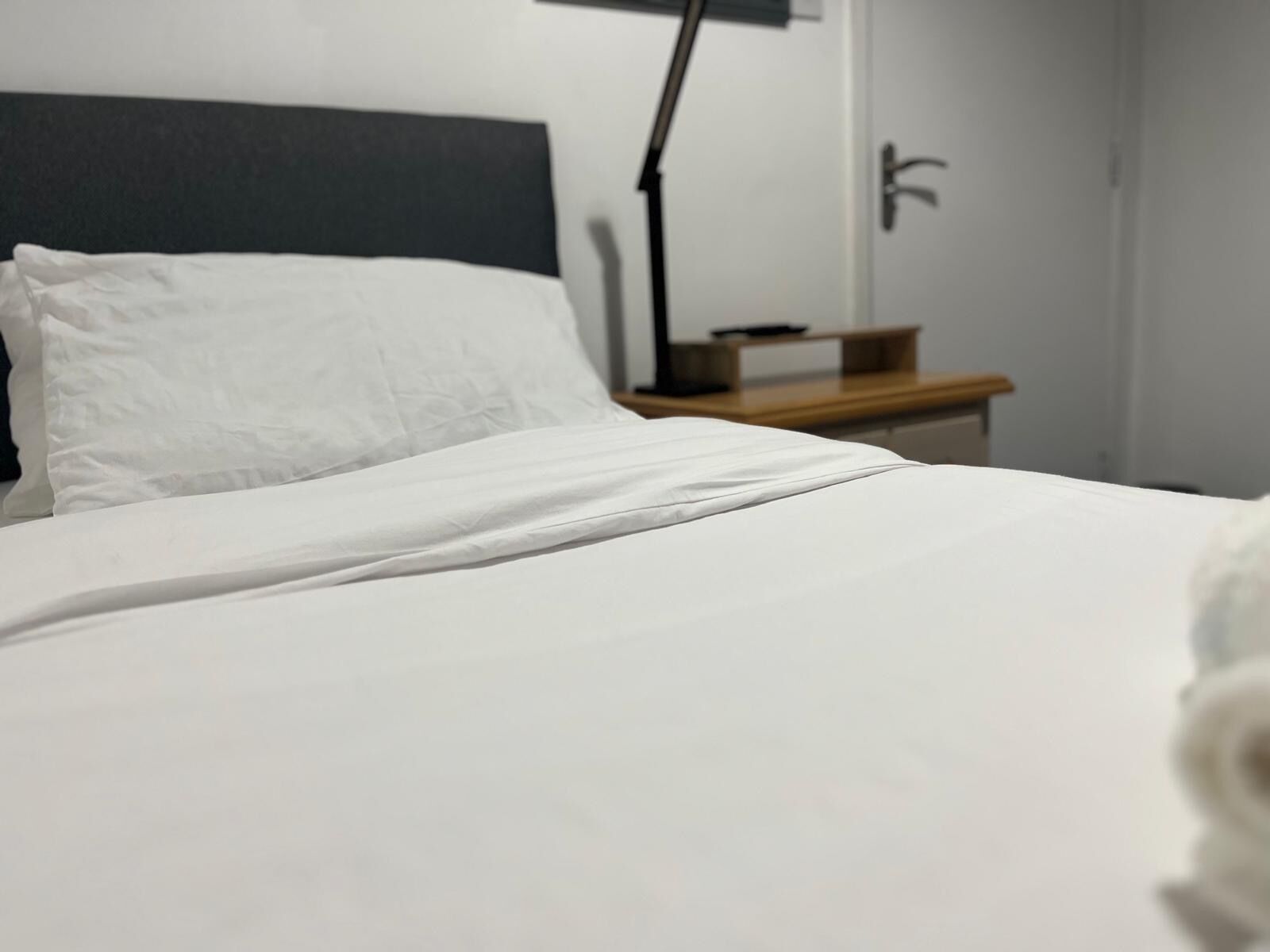 A neatly made bed with white linens in a hotel room.