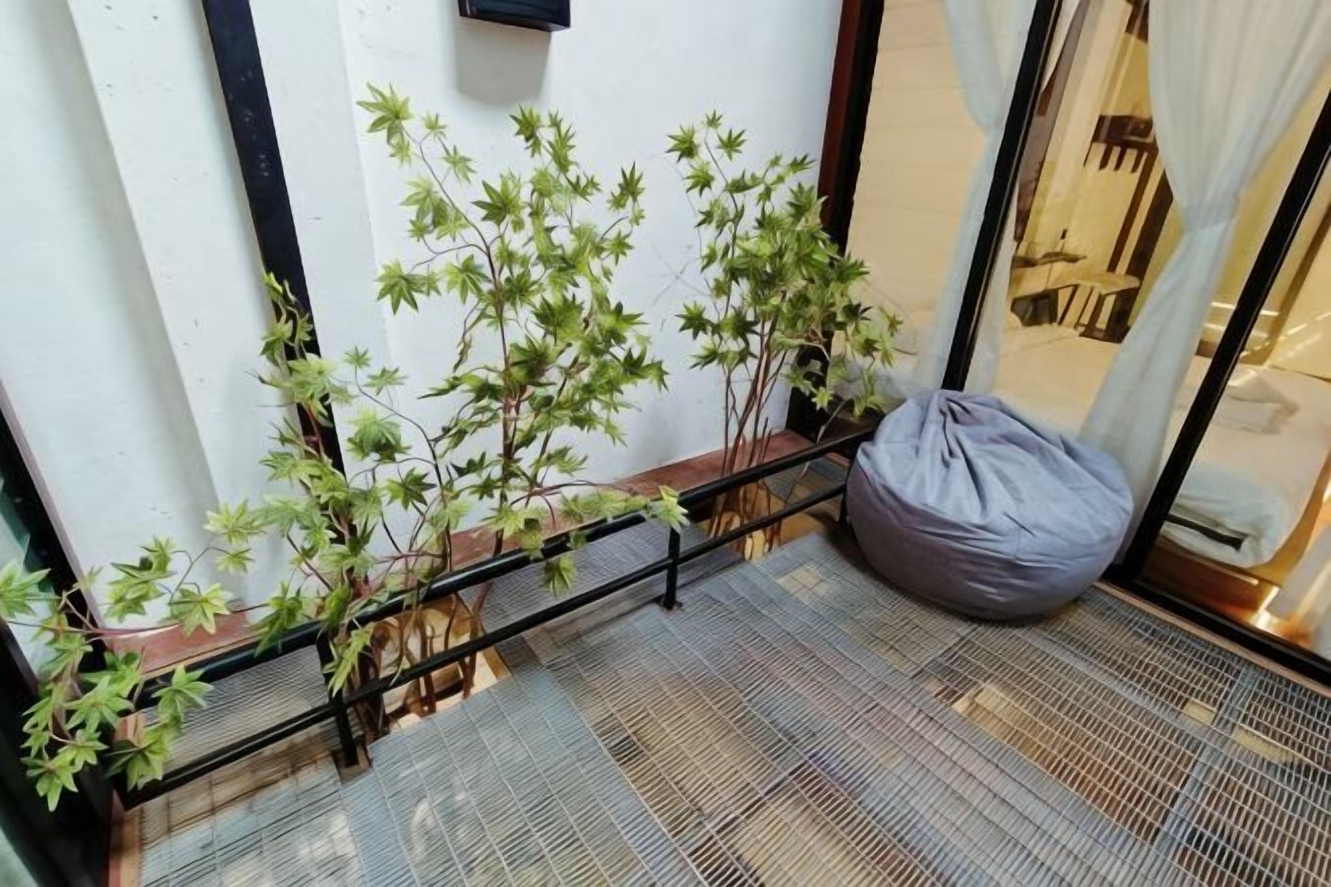 A corner with a plant, a bean bag, and a patterned floor.