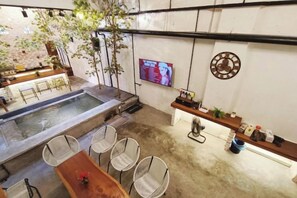Un espace piscine doté d’un bar et de sièges, d’un écran de télévision et d’une horloge murale.