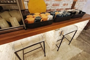 Een koffiehoek met mokken en een geel bord.
