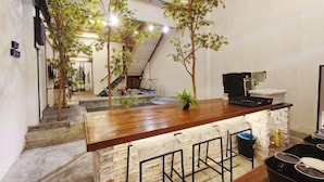 A kitchen with a wooden countertop, bar stools, a sink, and a staircase leading to an upper level. - Ruma Papanz Moden 3Br 19 Pax by Jeffery Lam Home Management (Melaka)