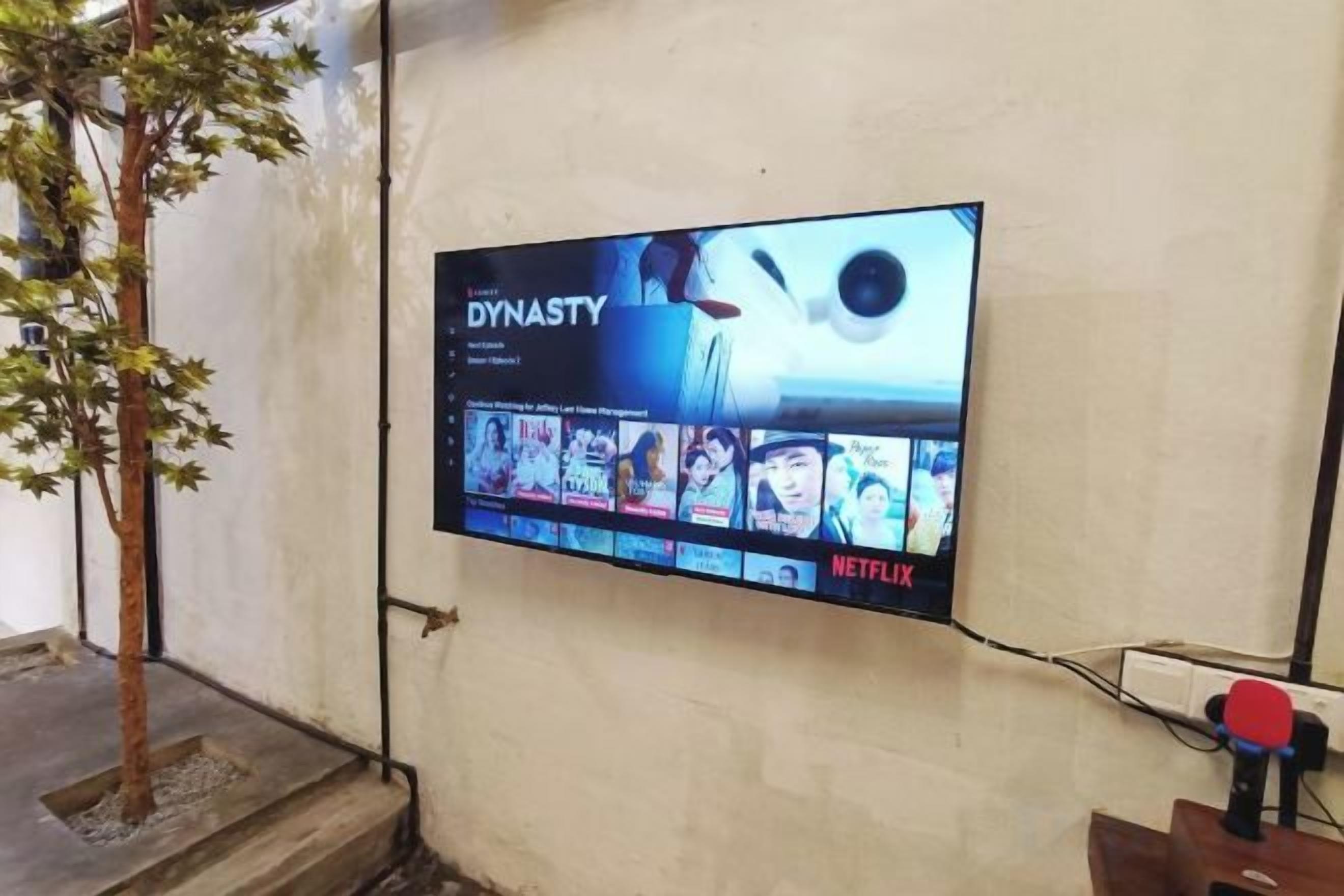 Ein an der Wand befestigtes Fernsehgerät zeigt das Netflix-Logo und die Sendung 'Dynasty'.