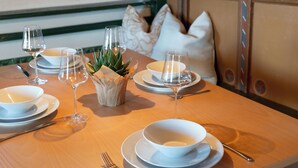 A dining table set with white plates, bowls, and wine glasses, accompanied by a small potted plant. - Idyllic apartment on the Ritten - peace, nature & views of the Dolomites. Mobilcard incl. (Trentino-Alto Adige)