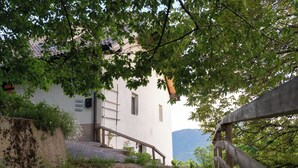 A building with a white exterior, a wooden staircase, and a view of a mountain in the background. - Idyllic apartment on the Ritten - peace, nature & views of the Dolomites. Mobilcard incl. (Trentino-Alto Adige)