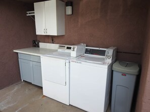 Un área de lavandería compacta con lavadora, secadora y un cubo de basura.