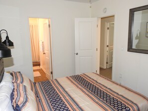Ein Schlafzimmer mit einem Bett, einer Nachttischlampe, einer Tür und einem Spiegel an der Wand.