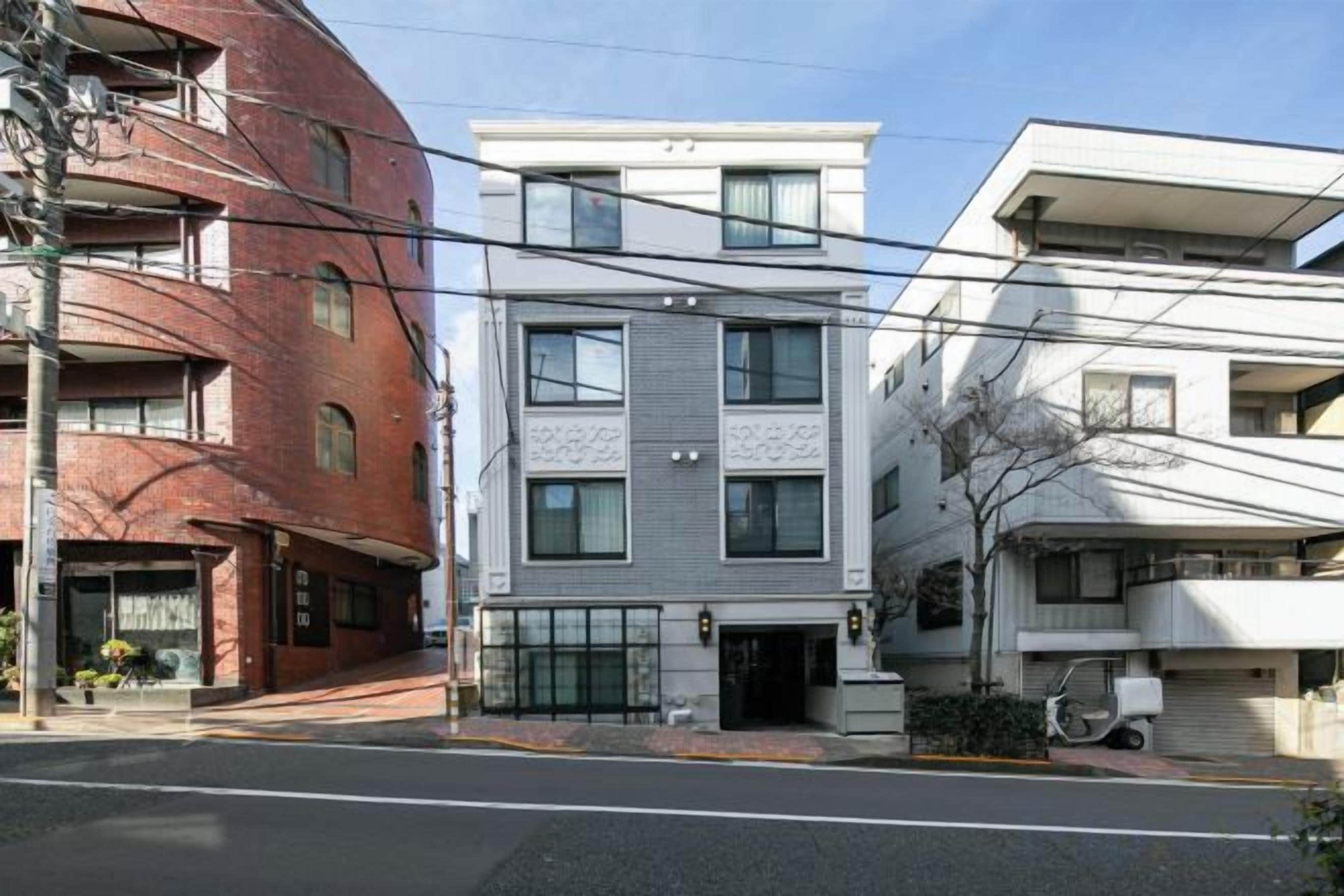 A multi-story residential building with a flat roof, a garage, and a small front yard.