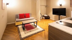 Una sala de estar moderna con un sofá, una mesa de centro, un televisor de pantalla plana y una cocina con un lavaplatos.