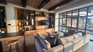 A modern living room with a sofa, a coffee table, and a TV. There is a kitchen area with shelves and a bar counter. - Cozy 1-bedroom studio in delightful Puerto Vallarta with AC (Puerto Vallarta)