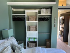 Una camera da letto con armadio a muro, un letto, un comodino e un angolo lavanderia.