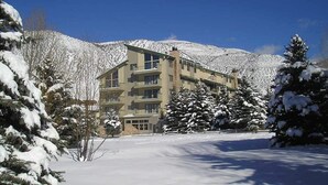 Un hôtel à plusieurs étages, avec un paysage enneigé et des montagnes en arrière-plan.